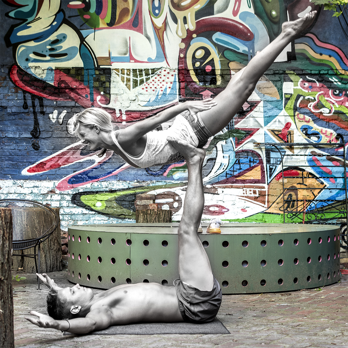 Partner acro balance session in front of a painted brick mural