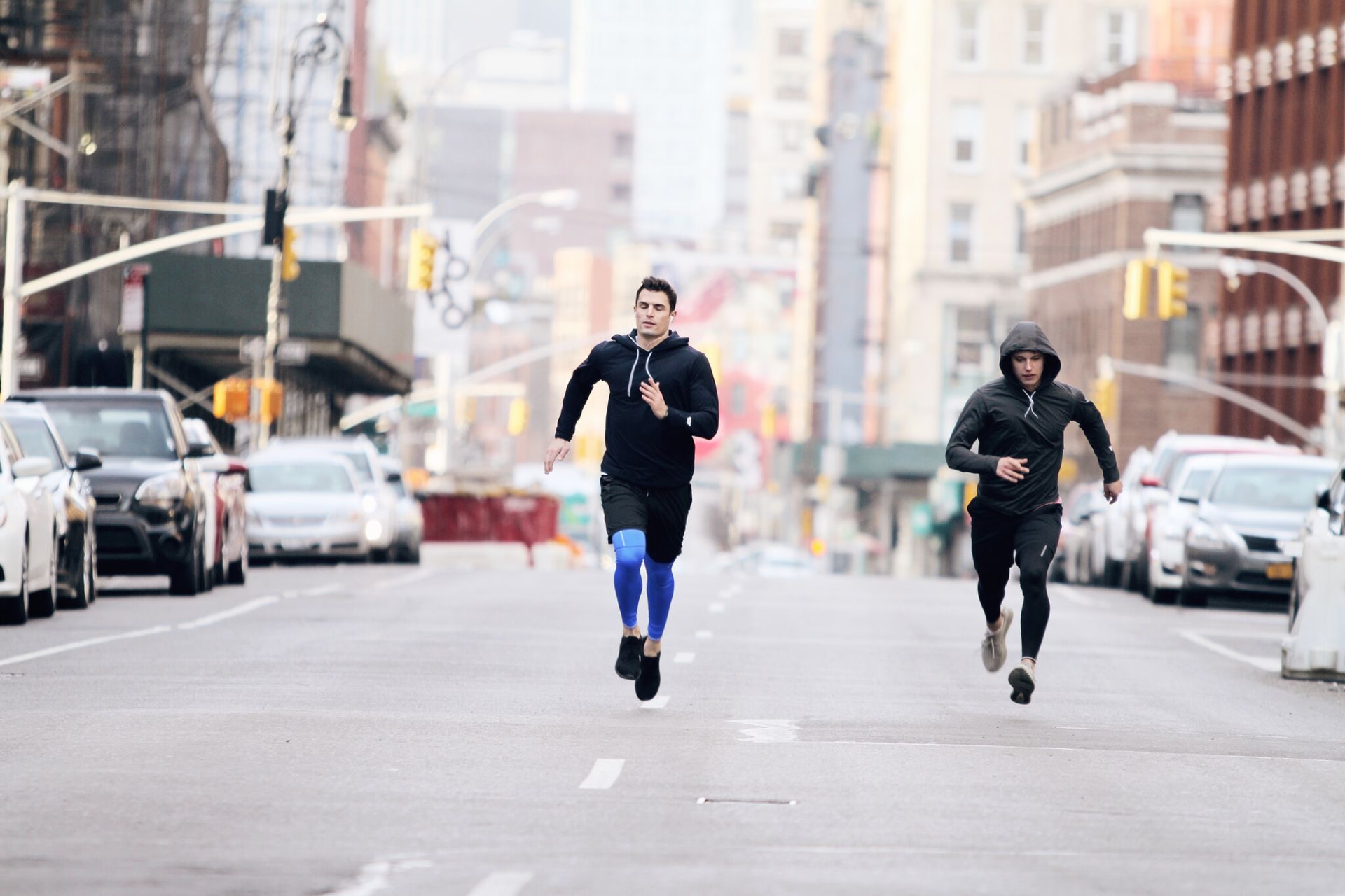 Two athletes sprinting down an empty city street at dawn